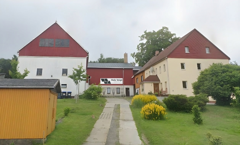 Ansicht des Firmenhofs in Reichenau mit roten und gelben Gebäuden, Zufahrt und grünen Sträuchern